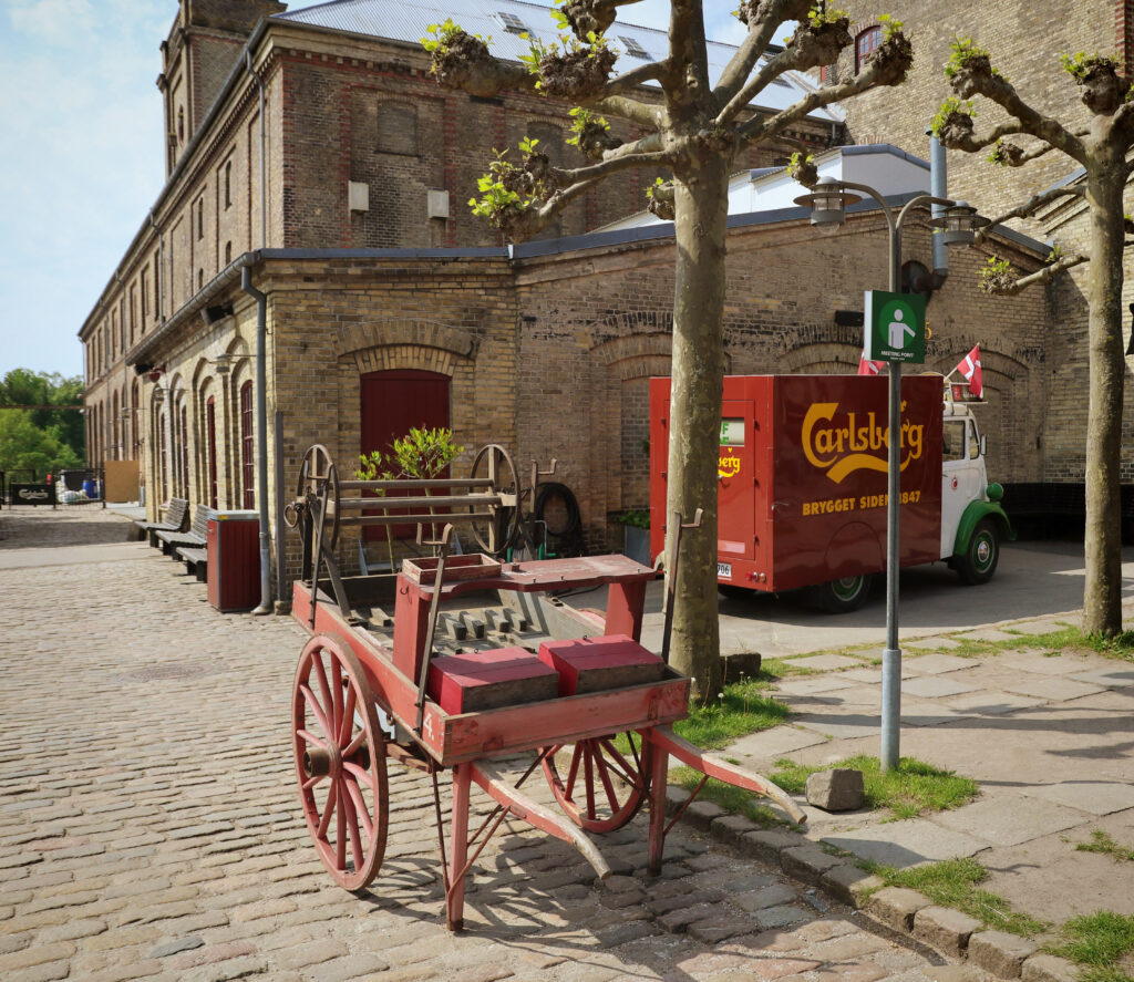 COPENHAGEN, DENMARK - MAY 18, 2018 the yard of the Old Carlsberg brewery in Copenhagen with with an old carriage in exposition and a Carlsberg beer distribution truck